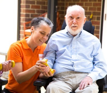 Allied Health Professional with elderly man exercising with hand weights